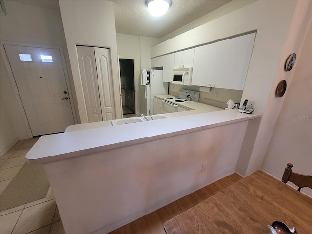 611 Tremont Greens Ln, Sun City Center, FL 33573 - kitchen featuring white appliances, a sink, light countertops, a peninsula, and light wood-style flooring