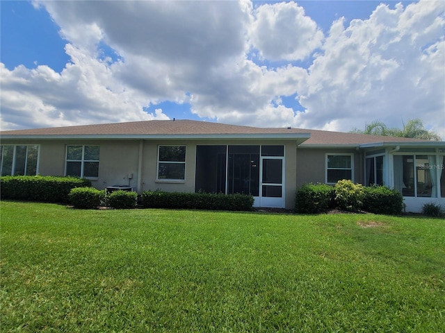 611 Tremont Greens Ln, Sun City Center, FL 33573 - rear view of house with a sunroom, stucco siding, and a lawn