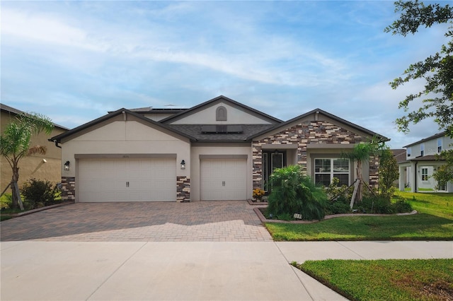 3091 King Fern Dr, Wimauma, FL 33598 - view of front of house with decorative driveway, stone siding, stucco siding, a garage, and roof mounted solar panels