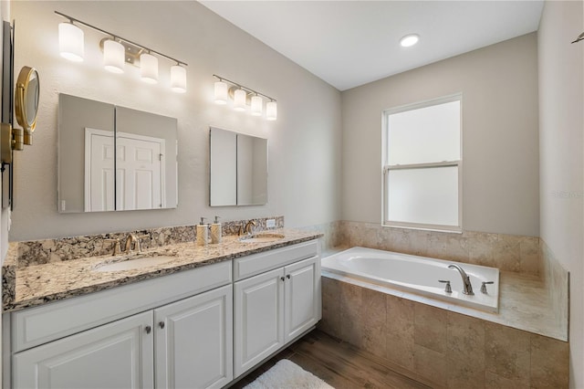 3091 King Fern Dr, Wimauma, FL 33598 - bathroom featuring double vanity, wood finished floors, and a garden tub