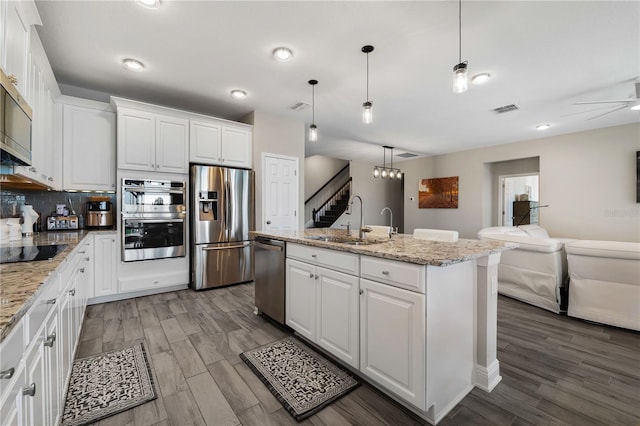 3091 King Fern Dr, Wimauma, FL 33598 - kitchen with stainless steel appliances, a sink, open floor plan, and white cabinetry