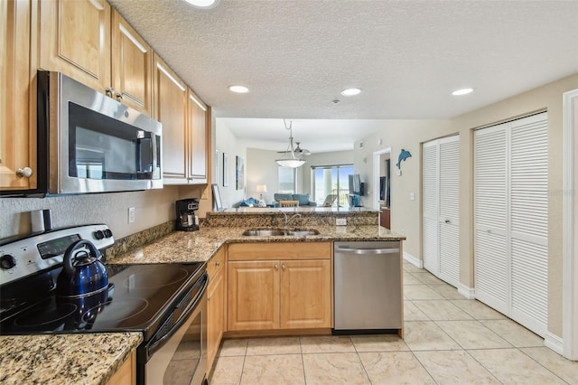 11605 Gulf Blvd Unit 506, Saint Petersburg, FL 33706 - kitchen featuring stainless steel appliances, a peninsula, a sink, light stone counters, and recessed lighting