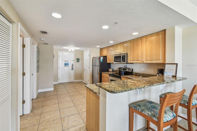 11605 Gulf Blvd Unit 506, Saint Petersburg, FL 33706 - kitchen with stainless steel appliances, a breakfast bar area, dark stone counters, a peninsula, and recessed lighting