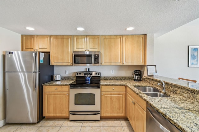11605 Gulf Blvd Unit 506, Saint Petersburg, FL 33706 - kitchen featuring appliances with stainless steel finishes, a sink, a textured ceiling, light stone countertops, and light tile patterned floors
