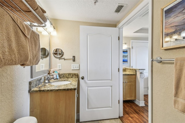 11605 Gulf Blvd Unit 506, Saint Petersburg, FL 33706 - bathroom featuring a textured wall, wood finished floors, vanity, a textured ceiling, and toilet