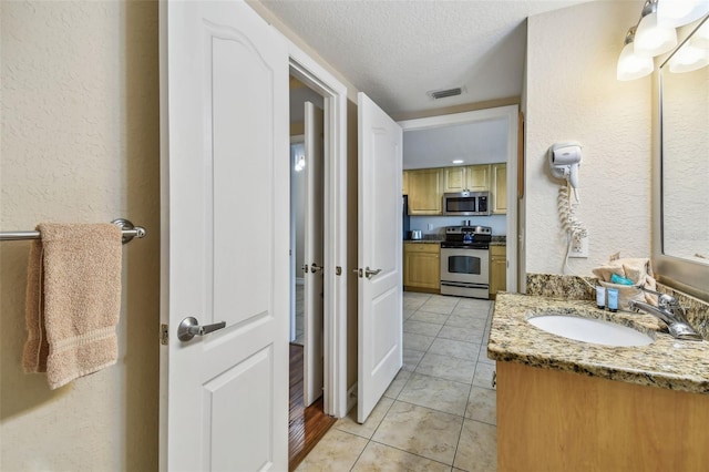 11605 Gulf Blvd Unit 506, Saint Petersburg, FL 33706 - bathroom featuring vanity, tile patterned flooring, a textured ceiling, and a textured wall