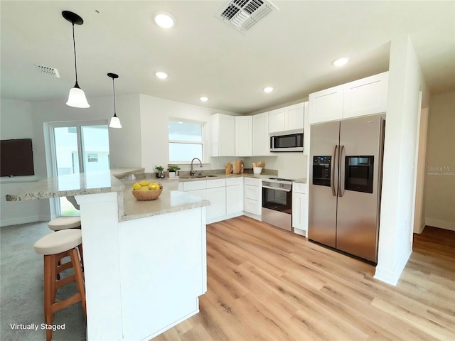 222 Carpenters Way Unit 71, Lakeland, FL 33805 - kitchen with appliances with stainless steel finishes, a sink, a peninsula, white cabinetry, and light stone countertops