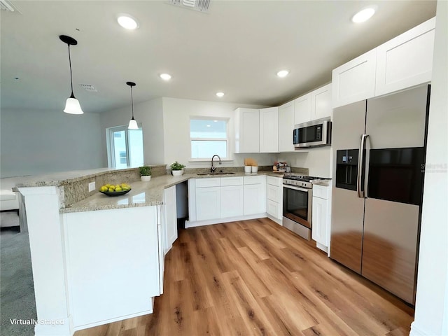 222 Carpenters Way Unit 71, Lakeland, FL 33805 - kitchen featuring appliances with stainless steel finishes, a sink, a peninsula, light stone countertops, and white cabinetry