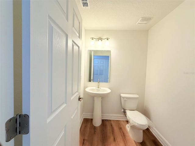 222 Carpenters Way Unit 71, Lakeland, FL 33805 - bathroom with toilet, wood finished floors, baseboards, a textured ceiling, and a sink