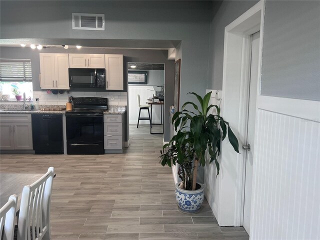 1631 St Mary Dr, Dunedin, FL 34698 - kitchen with black appliances, a sink, tasteful backsplash, light wood-type flooring, and light stone countertops