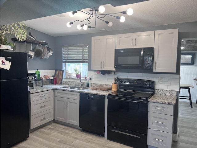 1631 St Mary Dr, Dunedin, FL 34698 - kitchen featuring black appliances, a sink, decorative backsplash, light wood-style flooring, and a chandelier