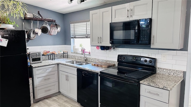 1631 St Mary Dr, Dunedin, FL 34698 - kitchen with black appliances, a sink, backsplash, light wood-style flooring, and light stone counters