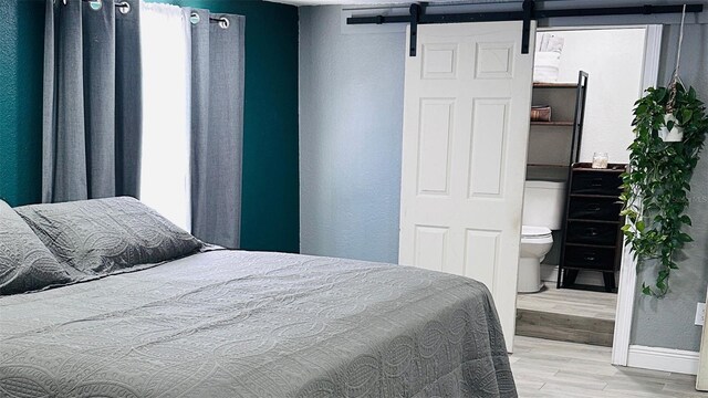 1631 St Mary Dr, Dunedin, FL 34698 - bedroom with a barn door, wood finished floors, and baseboards