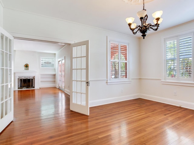 4521 W Azeele St, Tampa, FL 33609 - unfurnished living room with a chandelier, light wood-style floors, crown molding, baseboards, and french doors