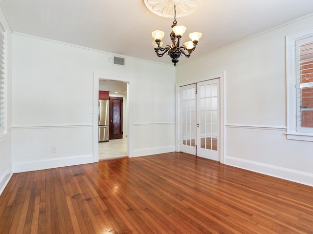 4521 W Azeele St, Tampa, FL 33609 - spare room featuring a chandelier, light wood finished floors, baseboards, ornamental molding, and french doors