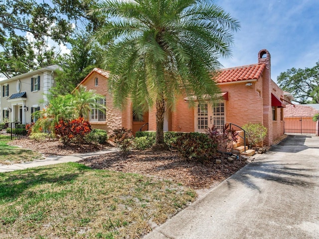 4521 W Azeele St, Tampa, FL 33609 - view of front facade with a tile roof, a chimney, stucco siding, and asphalt driveway