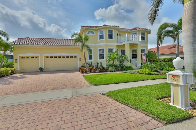 6468 Rubia Cir, Apollo Beach, FL 33572 - mediterranean / spanish-style home with a balcony, decorative driveway, a tiled roof, an attached garage, and a front lawn