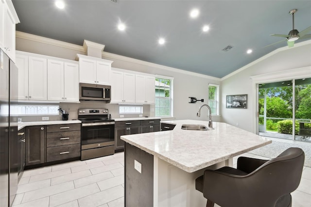 7991 Lake James Blvd, Lakeland, FL 33810 - kitchen with appliances with stainless steel finishes, a sink, white cabinetry, ornamental molding, and a center island with sink