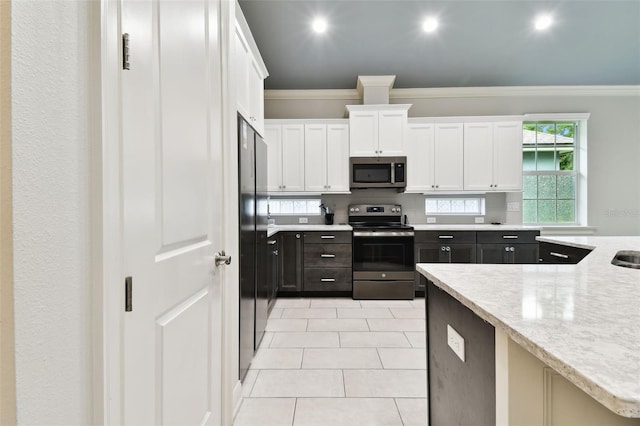 7991 Lake James Blvd, Lakeland, FL 33810 - kitchen with appliances with stainless steel finishes, crown molding, white cabinets, light tile patterned flooring, and light stone counters