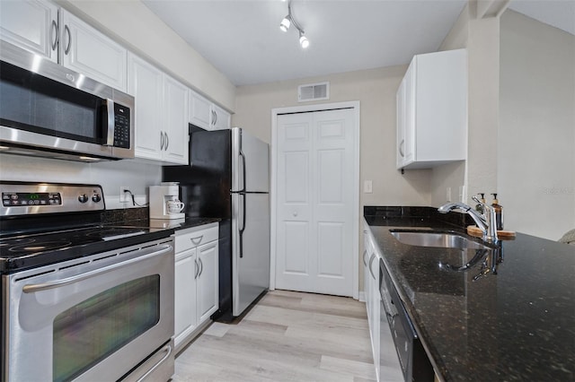 3301 Haviland Ct Unit 203, Palm Harbor, FL 34684 - kitchen with stainless steel appliances, a sink, white cabinets, light wood finished floors, and dark stone countertops