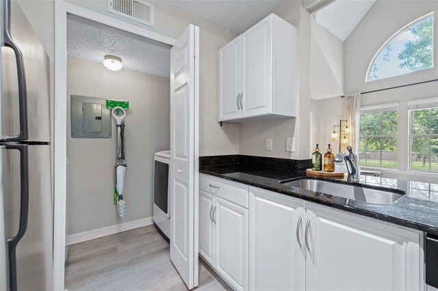 3301 Haviland Ct Unit 203, Palm Harbor, FL 34684 - kitchen with freestanding refrigerator, a sink, dark stone countertops, white cabinetry, and electric panel