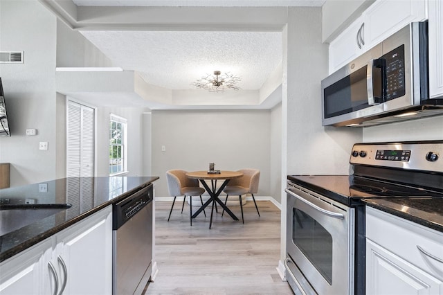 3301 Haviland Ct Unit 203, Palm Harbor, FL 34684 - kitchen featuring stainless steel appliances, a textured ceiling, white cabinetry, and dark stone counters