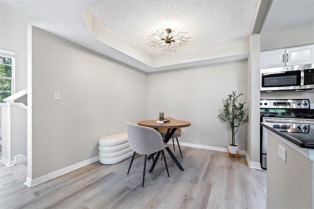 3301 Haviland Ct Unit 203, Palm Harbor, FL 34684 - dining area featuring a textured ceiling, light wood-style flooring, and baseboards