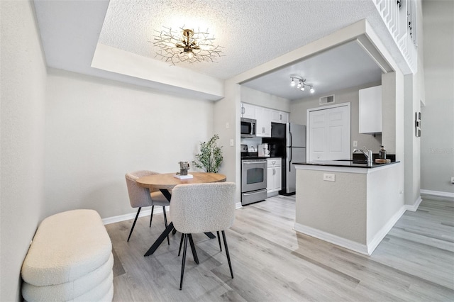 3301 Haviland Ct Unit 203, Palm Harbor, FL 34684 - kitchen with appliances with stainless steel finishes, dark countertops, a sink, white cabinets, and light wood-style floors