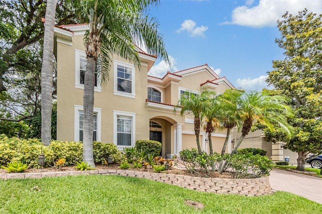 2354 Messenger Cir, Safety Harbor, FL 34695 - view of front of house with stucco siding, driveway, a front lawn, and a tile roof