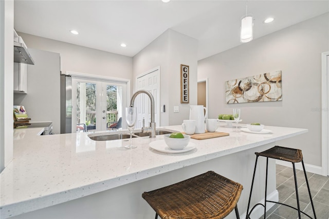 6433 Werner Ave, New Port Richey, FL 34652 - kitchen featuring a sink, a kitchen breakfast bar, wall chimney exhaust hood, light stone counters, and french doors