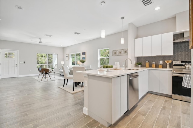 6433 Werner Ave, New Port Richey, FL 34652 - kitchen with appliances with stainless steel finishes, open floor plan, backsplash, wall chimney exhaust hood, and white cabinets