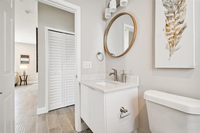 6433 Werner Ave, New Port Richey, FL 34652 - bathroom with toilet, a closet, vanity, wood finished floors, and baseboards