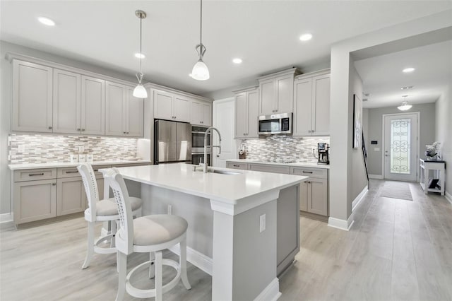 33287 Sycamore Leaf Dr, Wesley Chapel, FL 33545 - kitchen with stainless steel appliances, a sink, backsplash, an island with sink, and light countertops