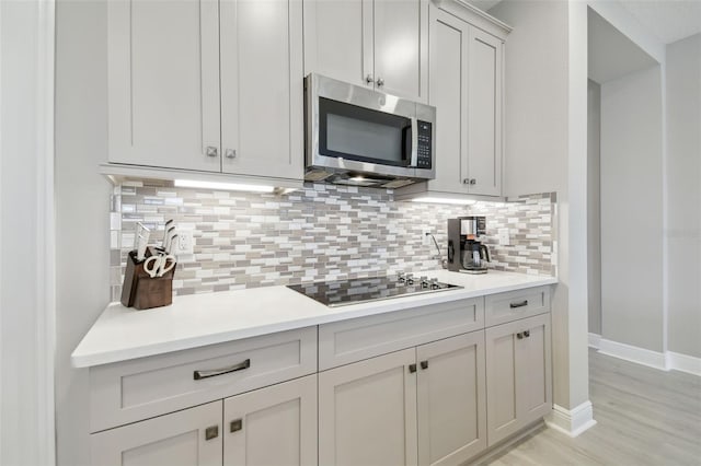 33287 Sycamore Leaf Dr, Wesley Chapel, FL 33545 - kitchen with stainless steel microwave, black electric stovetop, light countertops, and tasteful backsplash
