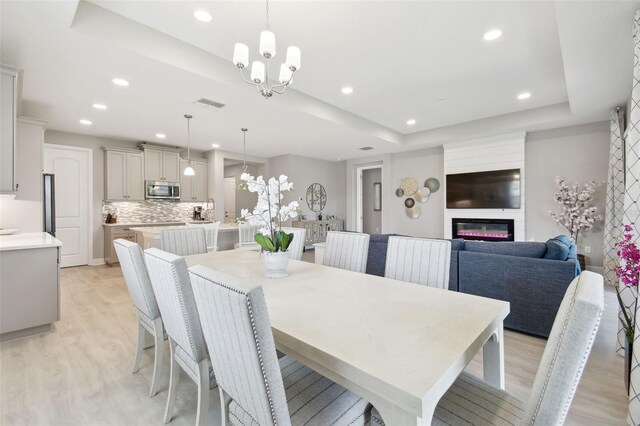 33287 Sycamore Leaf Dr, Wesley Chapel, FL 33545 - dining area with light wood-style floors, recessed lighting, a large fireplace, a chandelier, and a tray ceiling