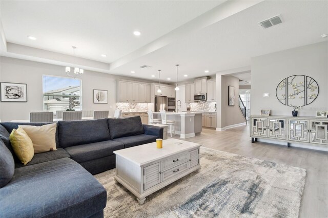 33287 Sycamore Leaf Dr, Wesley Chapel, FL 33545 - living area with light wood-type flooring, a chandelier, recessed lighting, and a tray ceiling