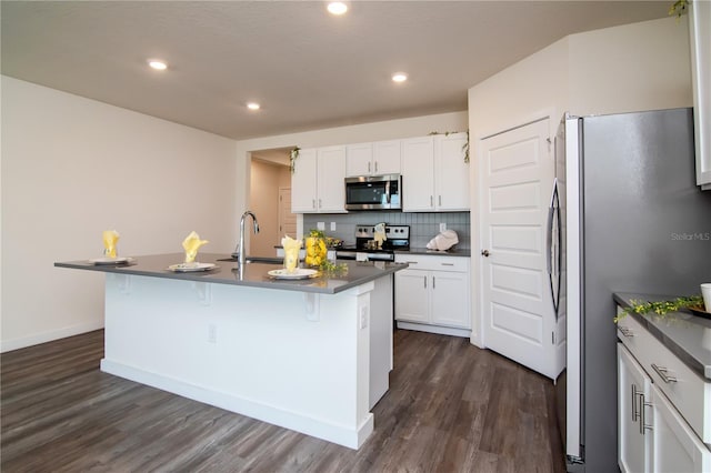 9795 Crescent Ray Dr, Wesley Chapel, FL 33545 - kitchen featuring stainless steel appliances, dark countertops, dark wood-style flooring, a kitchen breakfast bar, and recessed lighting
