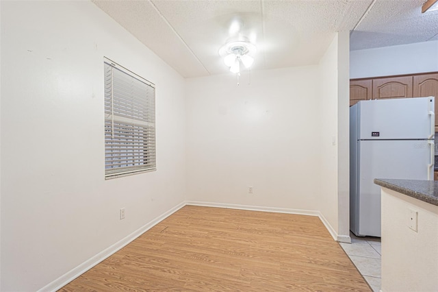 4708 Michael Ct Unit 104, Tampa, FL 33614 - unfurnished dining area featuring light wood finished floors, a textured ceiling, baseboards, and a ceiling fan