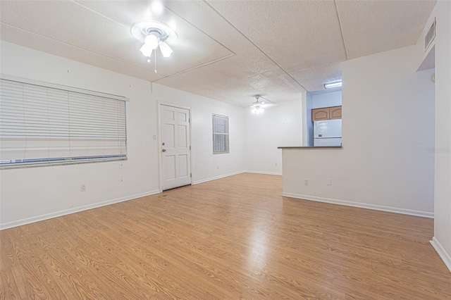 4708 Michael Ct Unit 104, Tampa, FL 33614 - empty room with ceiling fan, a textured ceiling, light wood finished floors, and baseboards