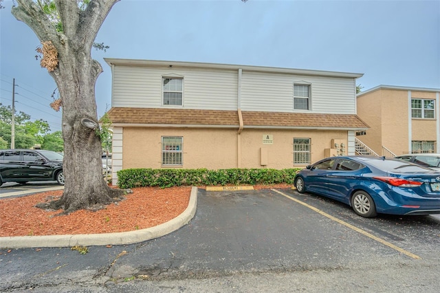 4708 Michael Ct Unit 104, Tampa, FL 33614 - view of front facade with uncovered parking, roof with shingles, and stucco siding