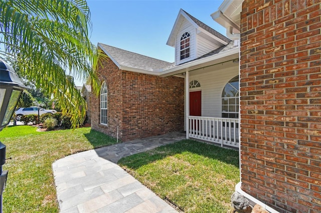 9709 Bay Colony Dr, Riverview, FL 33578 - property entrance featuring a porch, a yard, brick siding, and roof with shingles