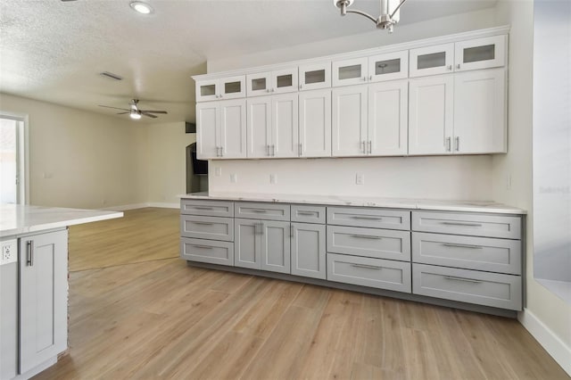 9709 Bay Colony Dr, Riverview, FL 33578 - kitchen featuring ceiling fan, light wood-style floors, baseboards, gray cabinetry, and glass insert cabinets