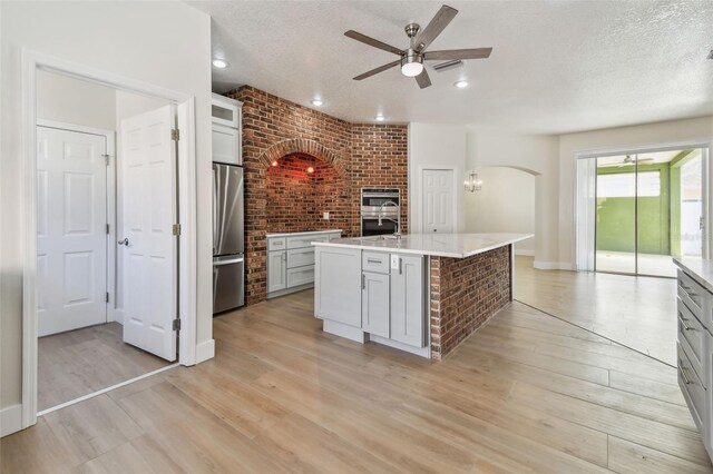 9709 Bay Colony Dr, Riverview, FL 33578 - kitchen featuring appliances with stainless steel finishes, ceiling fan, a textured ceiling, arched walkways, and light countertops