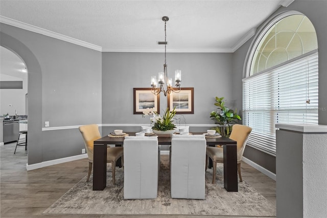 12009 Wandsworth Dr, Tampa, FL 33626 - dining space with wood finished floors, arched walkways, a chandelier, crown molding, and baseboards