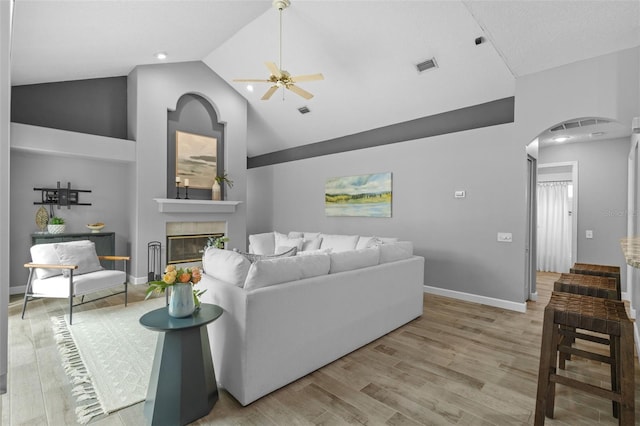 12009 Wandsworth Dr, Tampa, FL 33626 - living area with arched walkways, wood finished floors, ceiling fan, a glass covered fireplace, and high vaulted ceiling