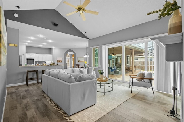 12009 Wandsworth Dr, Tampa, FL 33626 - living room featuring ceiling fan, arched walkways, light wood-style floors, and high vaulted ceiling