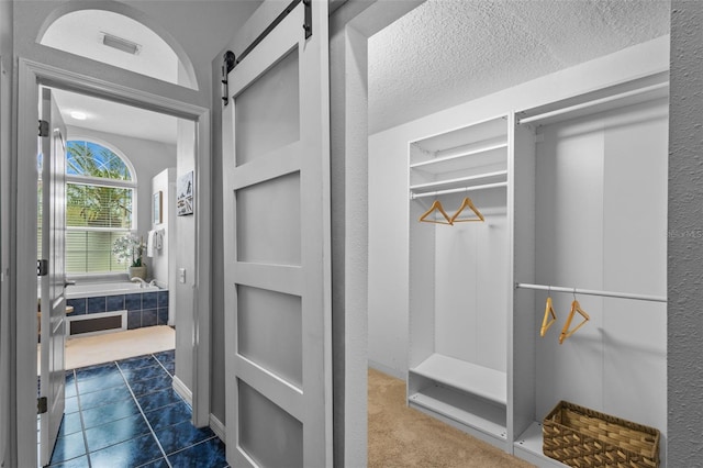 12009 Wandsworth Dr, Tampa, FL 33626 - walk in closet with a barn door and dark tile patterned floors