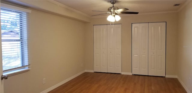1841 Georgia Ave, Palm Harbor, FL 34683 - unfurnished bedroom featuring two closets, multiple windows, wood finished floors, and ornamental molding