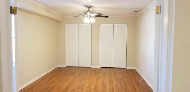 1841 Georgia Ave, Palm Harbor, FL 34683 - unfurnished bedroom with light wood-style floors, two closets, crown molding, baseboards, and a ceiling fan
