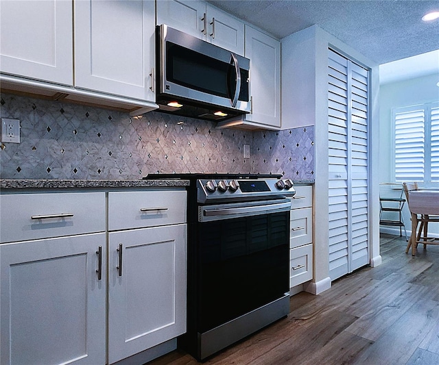 6060 Shore Blvd S Unit 903, Gulfport, FL 33707 - kitchen with stainless steel appliances, dark wood-type flooring, tasteful backsplash, white cabinetry, and baseboards